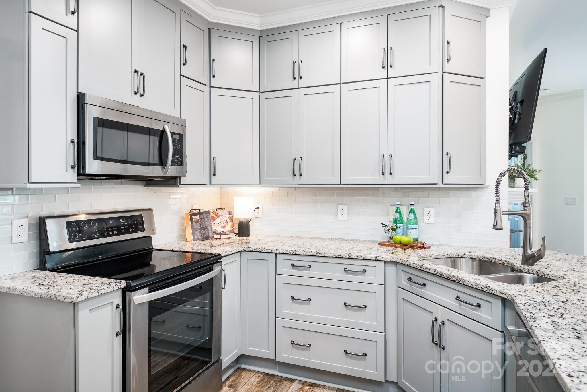 860 Jetton Street, Unit 64 Davidson, NC 28036 - Photo 6 of 33 a kitchen with granite countertop white cabinets stainless steel appliances and a sink