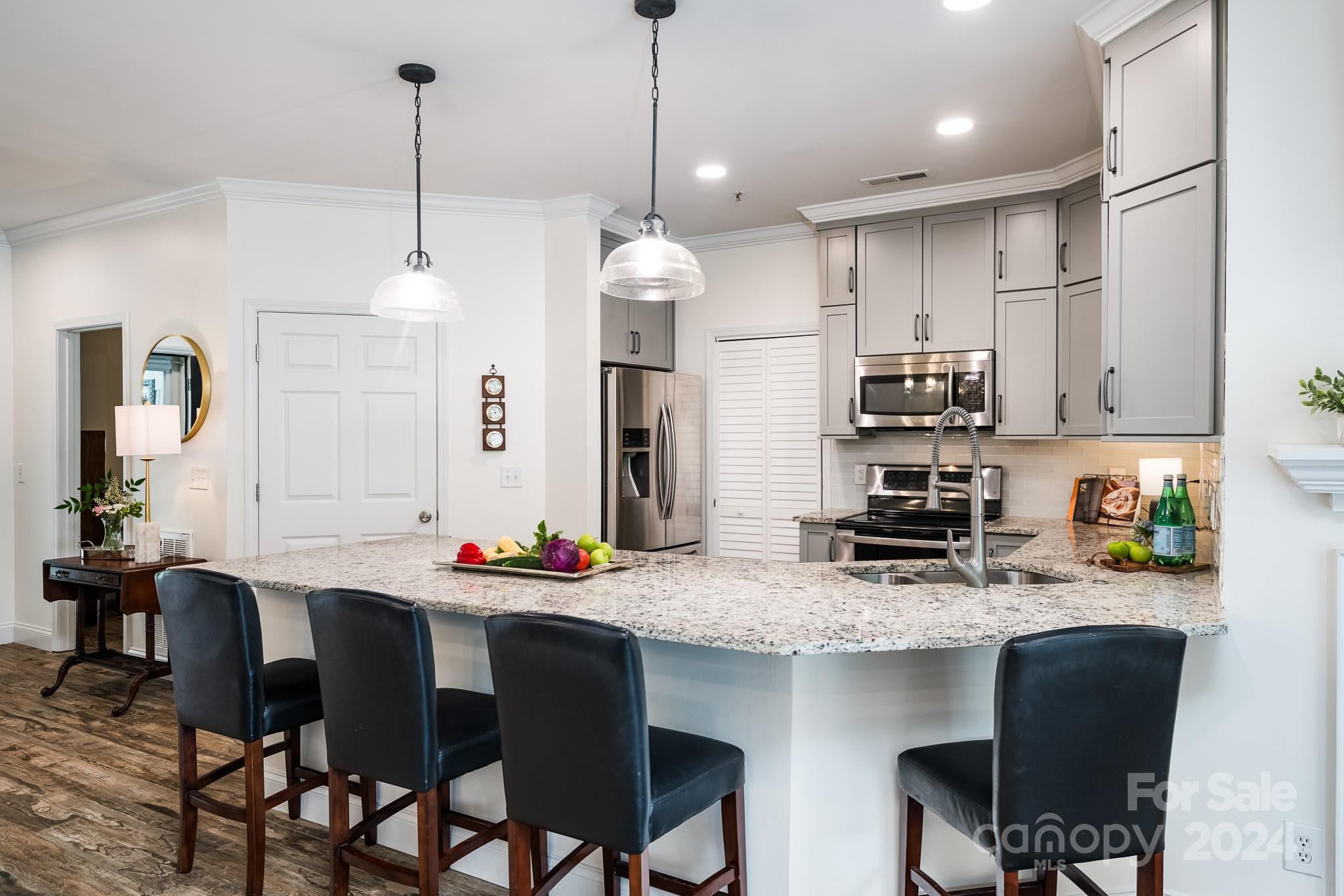 860 Jetton Street, Unit 64 Davidson, NC 28036 - Photo 7 of 33 a kitchen with stainless steel appliances a sink a stove a refrigerator and chairs