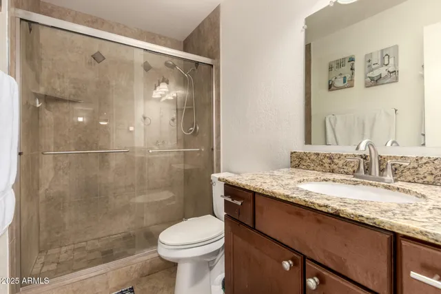 a bathroom with a granite countertop sink a toilet and a shower