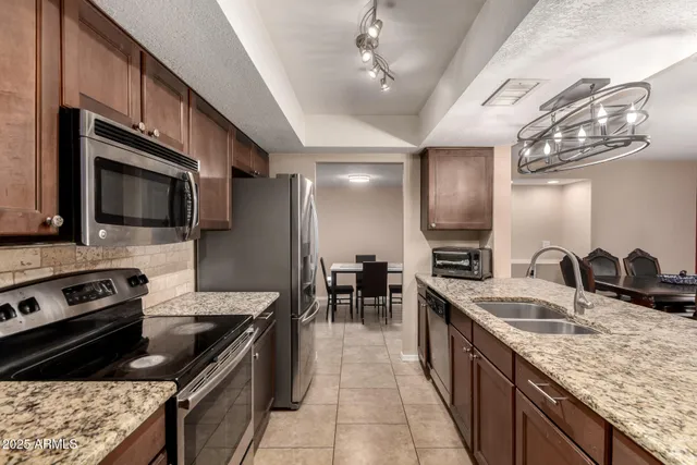a kitchen with stainless steel appliances granite countertop a sink stove and refrigerator