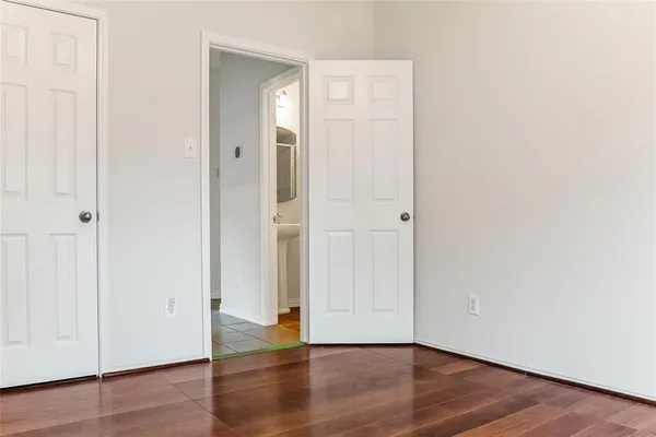 an empty room with wooden floor & closet area