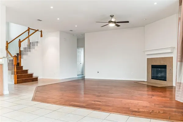 a view of an empty room and wooden floor entryway and a kitchen