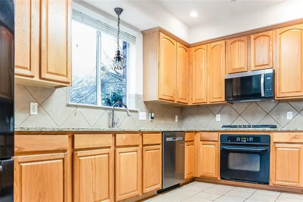 a kitchen with granite countertop a stove top oven cabinetry a sink and a window