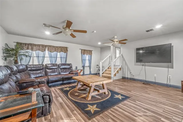 a living room with furniture a flat screen tv and a ceiling fan
