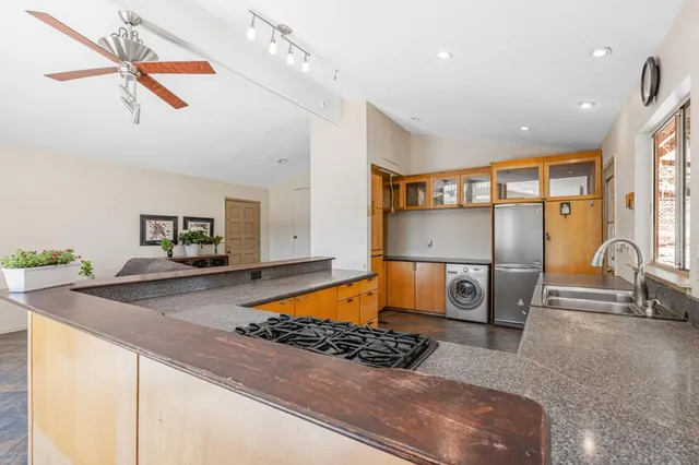 a living room with stainless steel appliances kitchen island granite countertop furniture a rug and a window