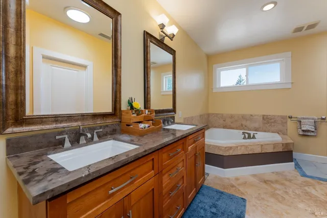 a bathroom with a tub double sink and mirror