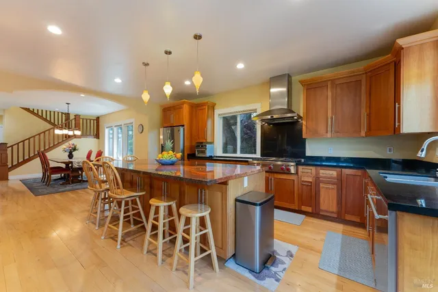 a kitchen with stainless steel appliances granite countertop a table chairs sink and cabinets