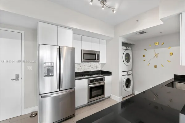 a kitchen with stainless steel appliances a refrigerator a stove and white cabinets