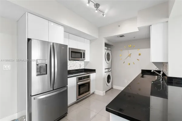 a kitchen with granite countertop a refrigerator stove and sink
