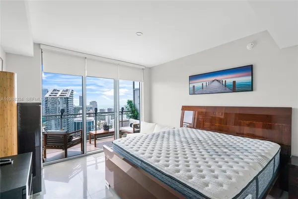 a bedroom with a large bed and a flat tv screen next to a window