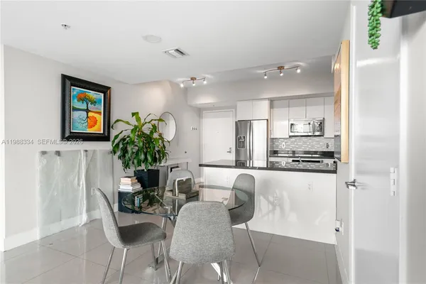 a dining room with kitchen island furniture a potted plant and a refrigerator
