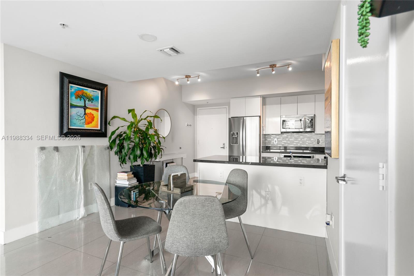 92 Southwest 3rd Street, Unit 4702 Miami, FL 33130 - Photo 9 of 47 a dining room with kitchen island furniture a potted plant and a refrigerator