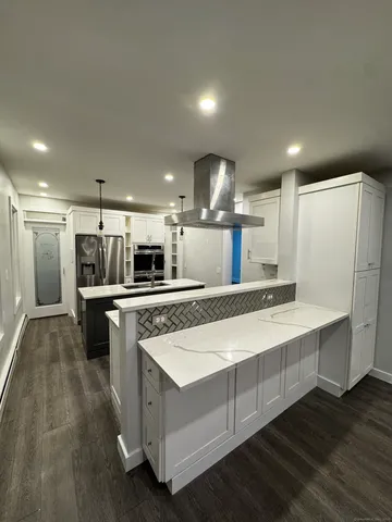 a large kitchen with a large counter top a sink stainless steel appliances and cabinets