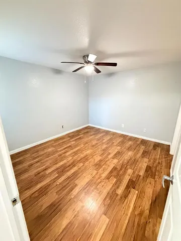 a view of room with a ceiling fan and wooden floor
