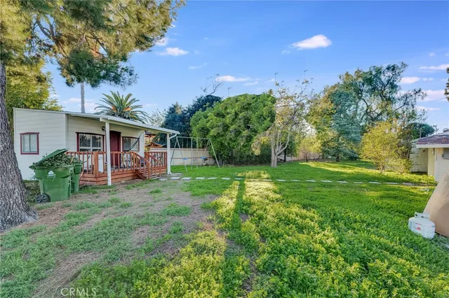 a view of a house with a big yard plants and large trees