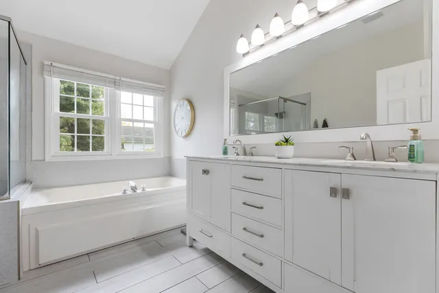 a bathroom with a tub a sink and mirror
