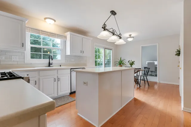 a kitchen with granite countertop a stove a sink a dining table and chairs with wooden floor