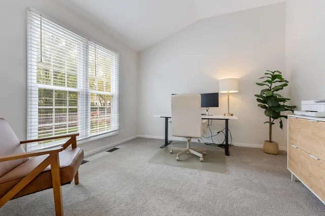 a view of a workspace with furniture and a window