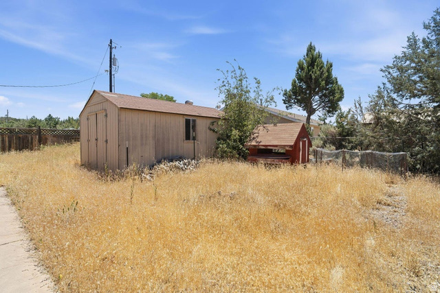 132 Rex Layne Drive Central, UT 84722 - Photo 32 of 39 Spacious outdoor area featuring a large utility shed with double doors and a window, a smaller red-painted structure, and a perimeter fence