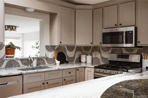 a kitchen with stainless steel appliances granite countertop a sink a stove and a microwave oven