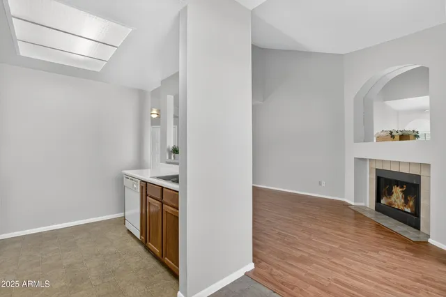 a view of kitchen and empty room with wooden floor