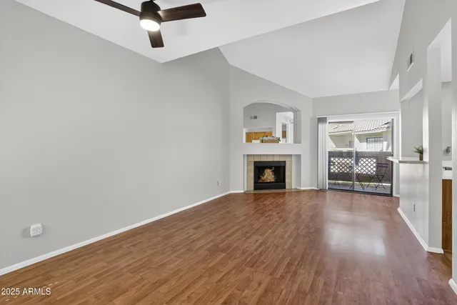 an empty room with wooden floor fireplace and windows