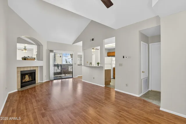 a view of an empty room with wooden floor and a fireplace