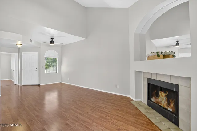 an empty room with wooden floor a fireplace and a window