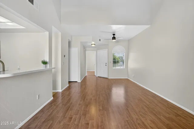 a view of an empty room with window and wooden floor