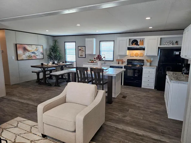 a living room with furniture a flat screen tv and kitchen view