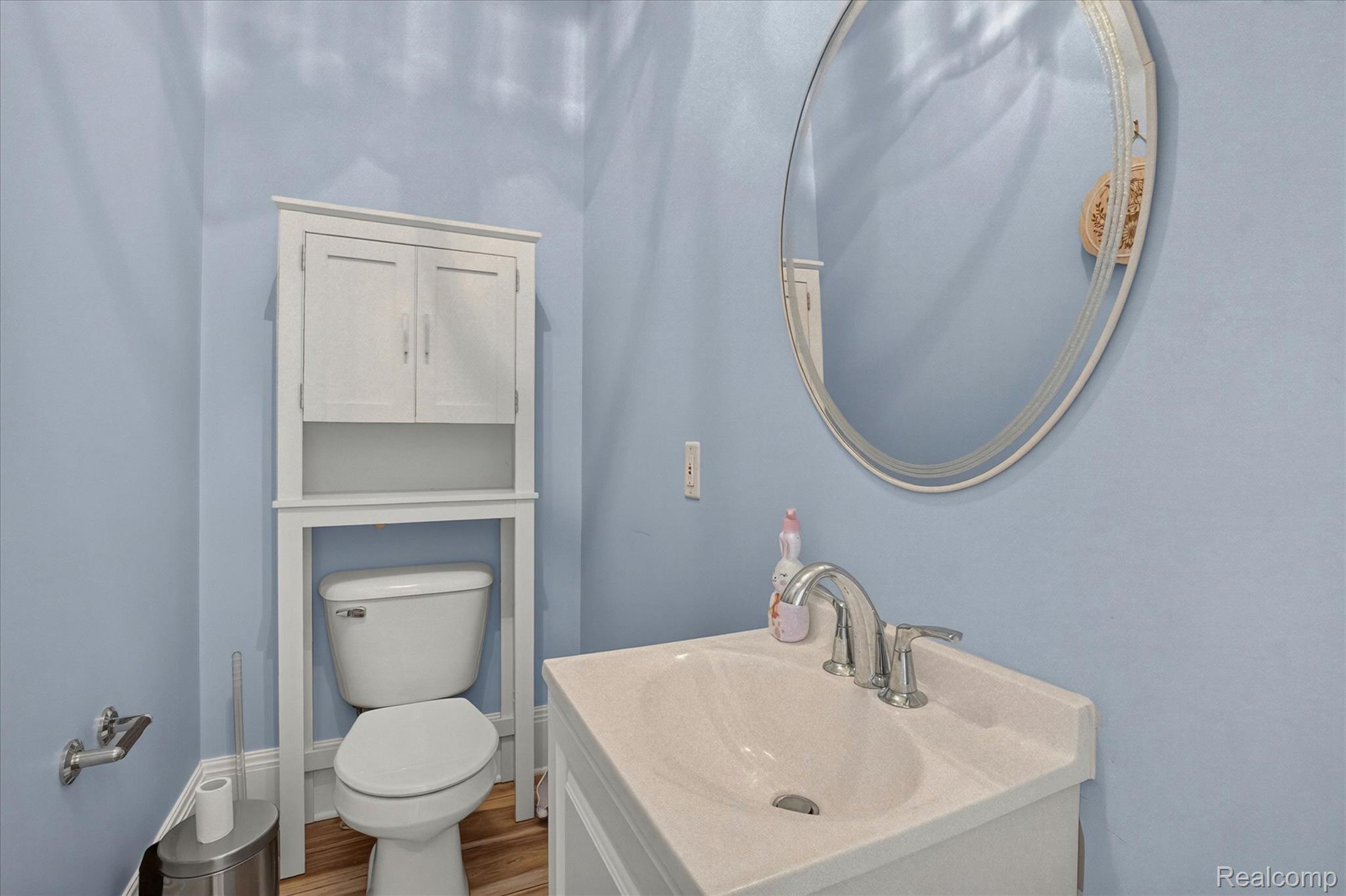 6524 Kelly Road Flushing, MI 48433 - Photo 27 of 47 Bathroom featuring light blue walls, a white vanity with an integrated sink, a chrome faucet, and an oval mirror