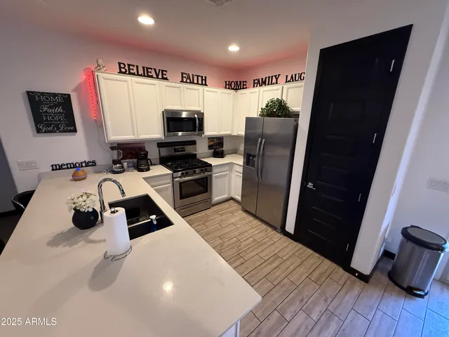 a kitchen with stainless steel appliances a stove a refrigerator a sink a microwave oven with wooden floor and cabinets