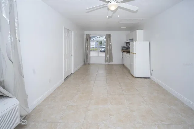 an empty room with chandelier fan and windows