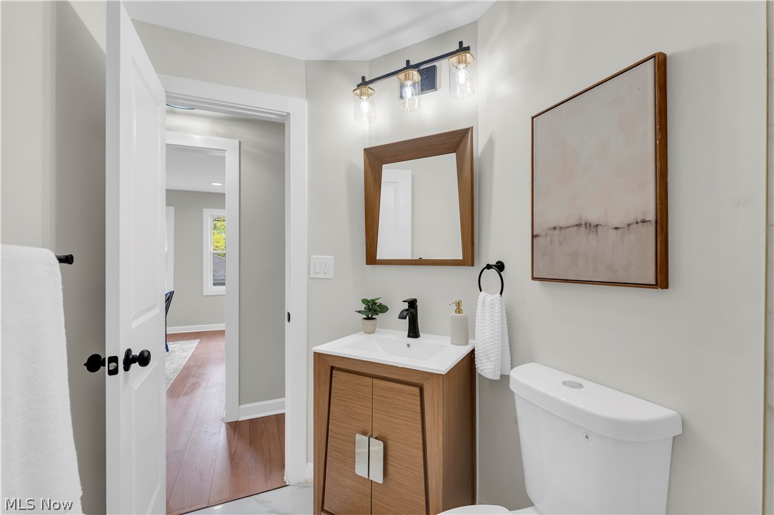 18155 Libby Road Maple Heights, OH 44137 - Photo 25 of 32 Bathroom featuring a wood-finish vanity with an integrated sink, matte black faucet, and a coordinating framed mirror