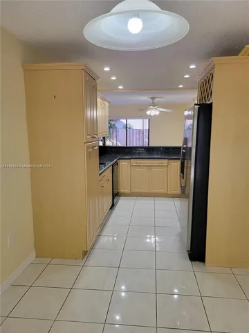 a view of an empty room with window and chandelier fan