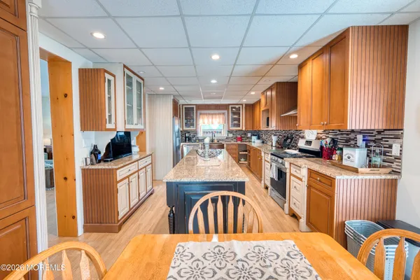 a kitchen with stainless steel appliances granite countertop a refrigerator a sink dishwasher a stove and white countertops with wooden floor