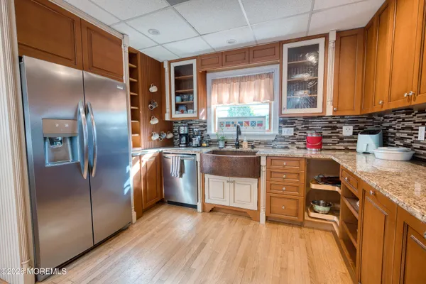 a kitchen with stainless steel appliances granite countertop a refrigerator a sink dishwasher a stove with wooden cabinets and floor