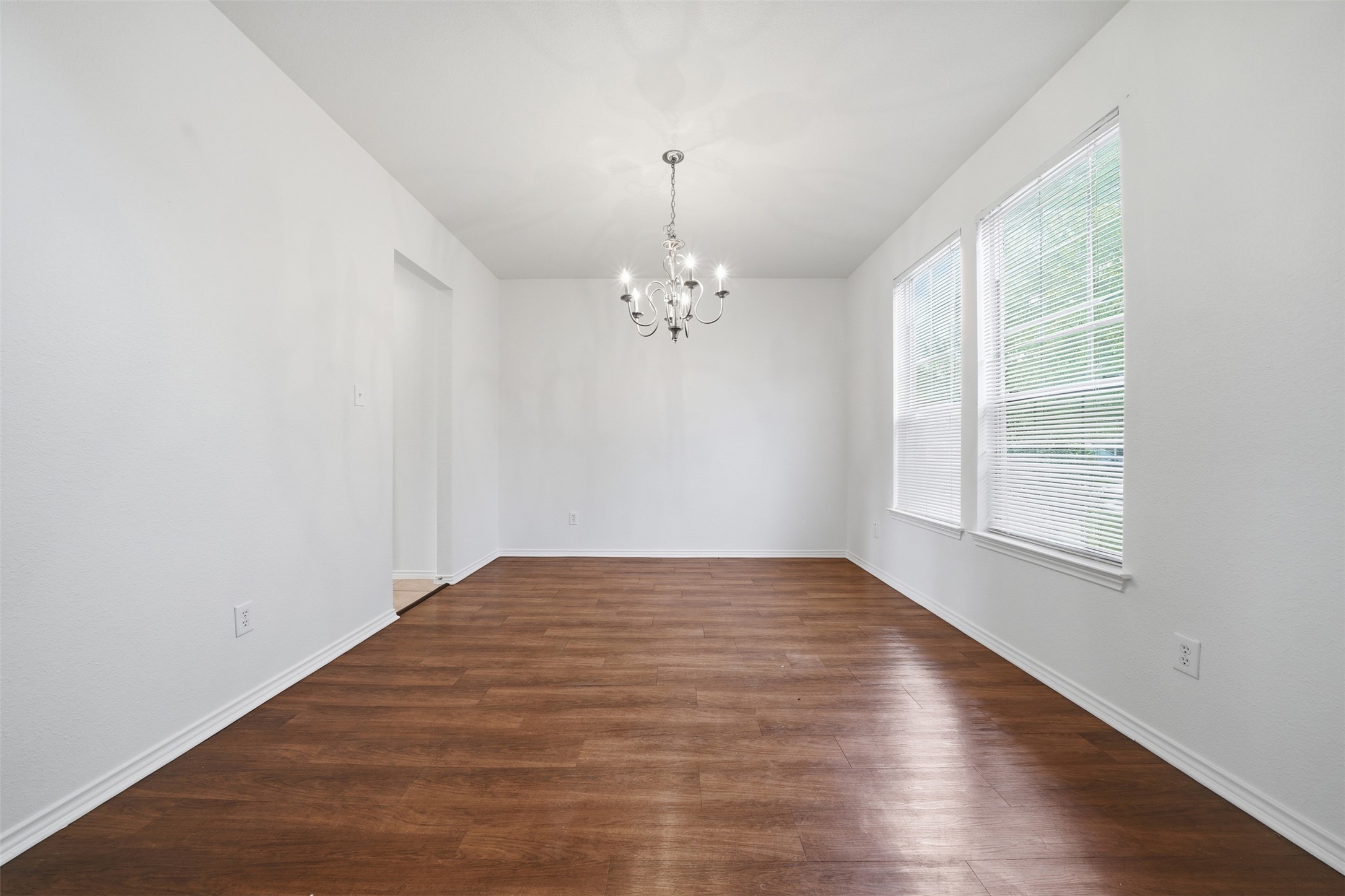 118 Invierno Street Kyle, TX 78640 - Photo 14 of 37 A classic chandelier illuminates the spacious dining area with rich hardwood flooring and generous natural light.