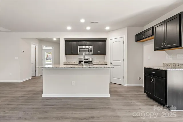 a large kitchen with stainless steel appliances granite countertop a stove a sink dishwasher and a refrigerator with wooden floor