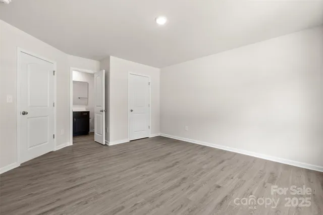 a view of an empty room with wooden floor and closet