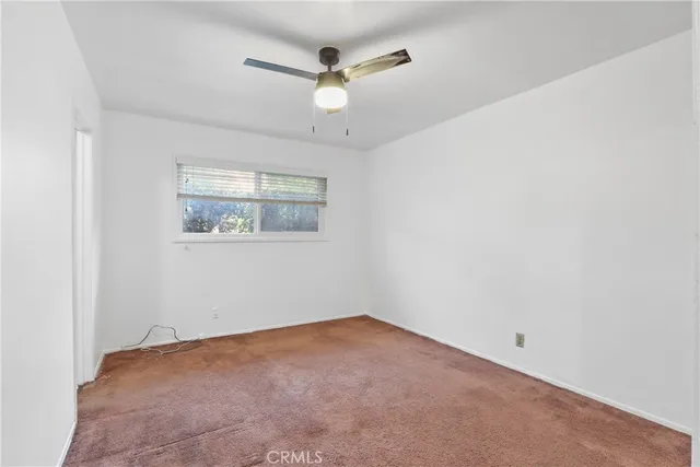 an empty room with a window and a fan
