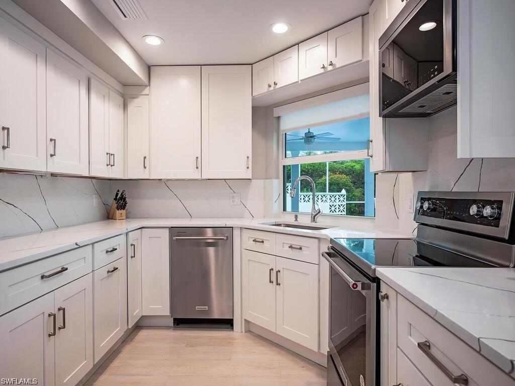 4856 Crayton Road Naples, FL 34103 - Photo 13 of 24 a kitchen with white cabinets and white appliances