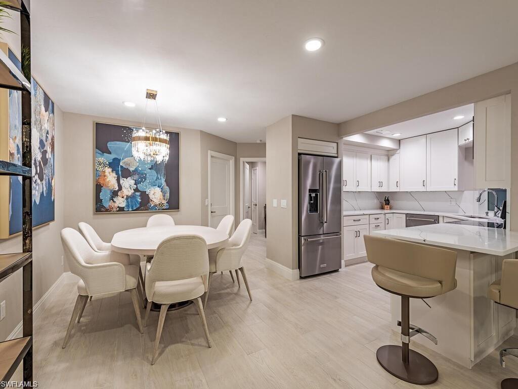 4856 Crayton Road Naples, FL 34103 - Photo 14 of 24 a kitchen with a dining table chairs refrigerator and cabinets