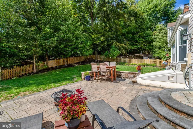 a view of a backyard with table and chairs potted plants and large tree