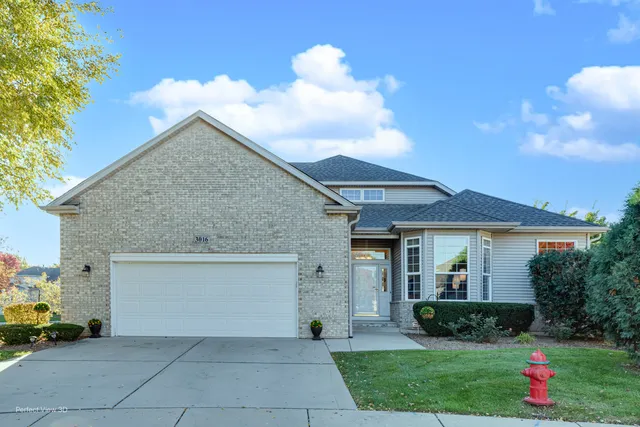 a view of a white house with a small yard and a large tree