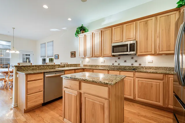 a kitchen with kitchen island granite countertop a sink cabinets and stainless steel appliances