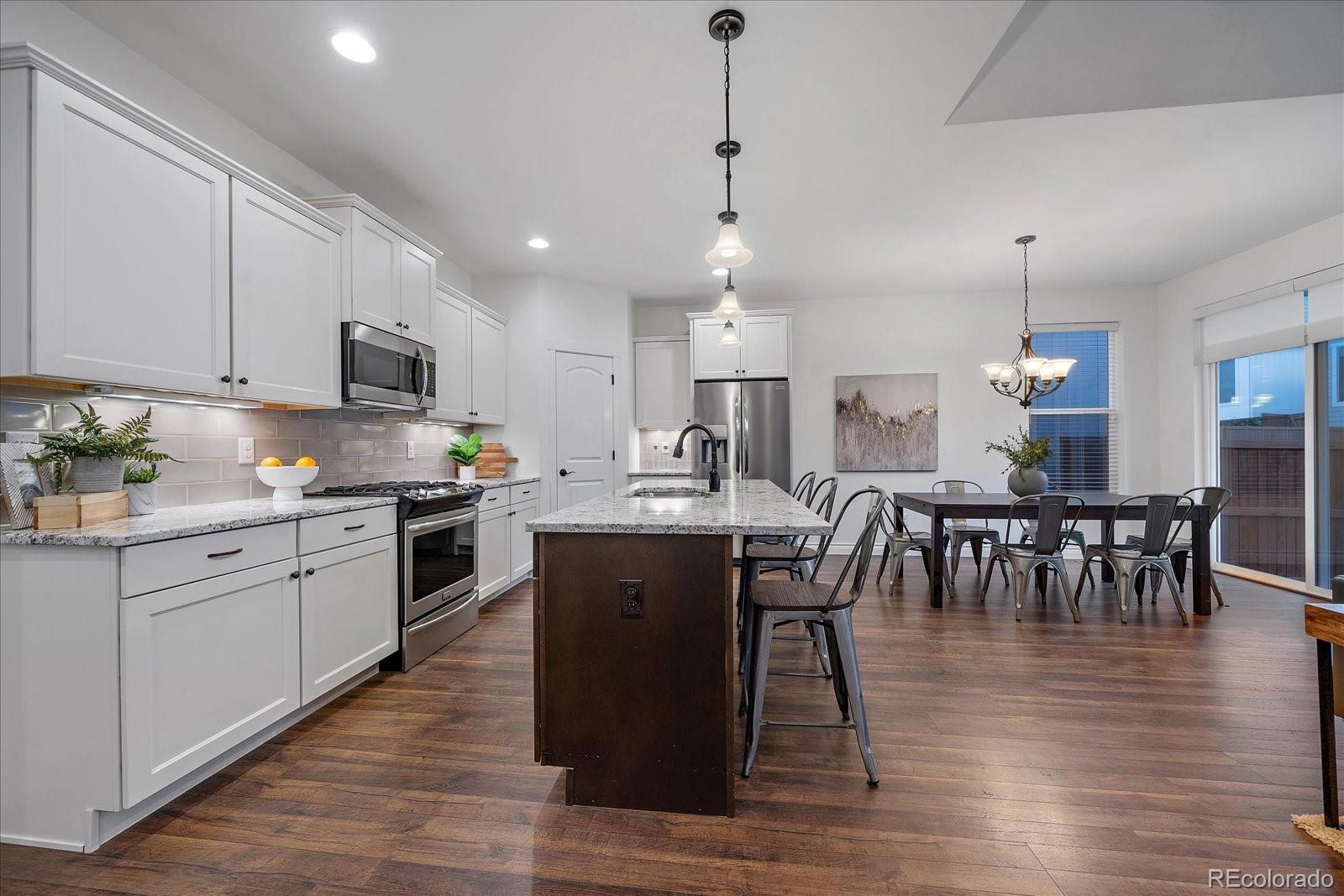 11526 Colony Loop Parker, CO 80138 - Photo 13 of 29 a kitchen with stainless steel appliances granite countertop a table chairs sink and cabinets