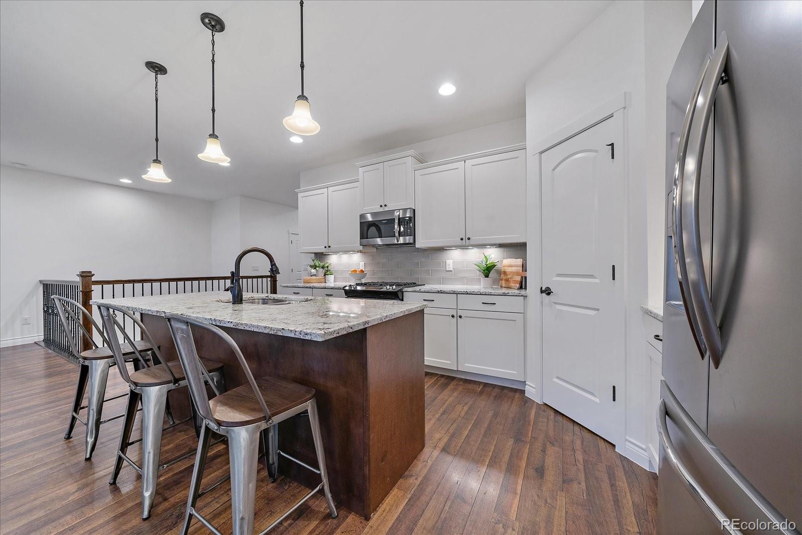 11526 Colony Loop Parker, CO 80138 - Photo 17 of 29 a kitchen with stainless steel appliances granite countertop a sink a stove a refrigerator and island with wooden floor
