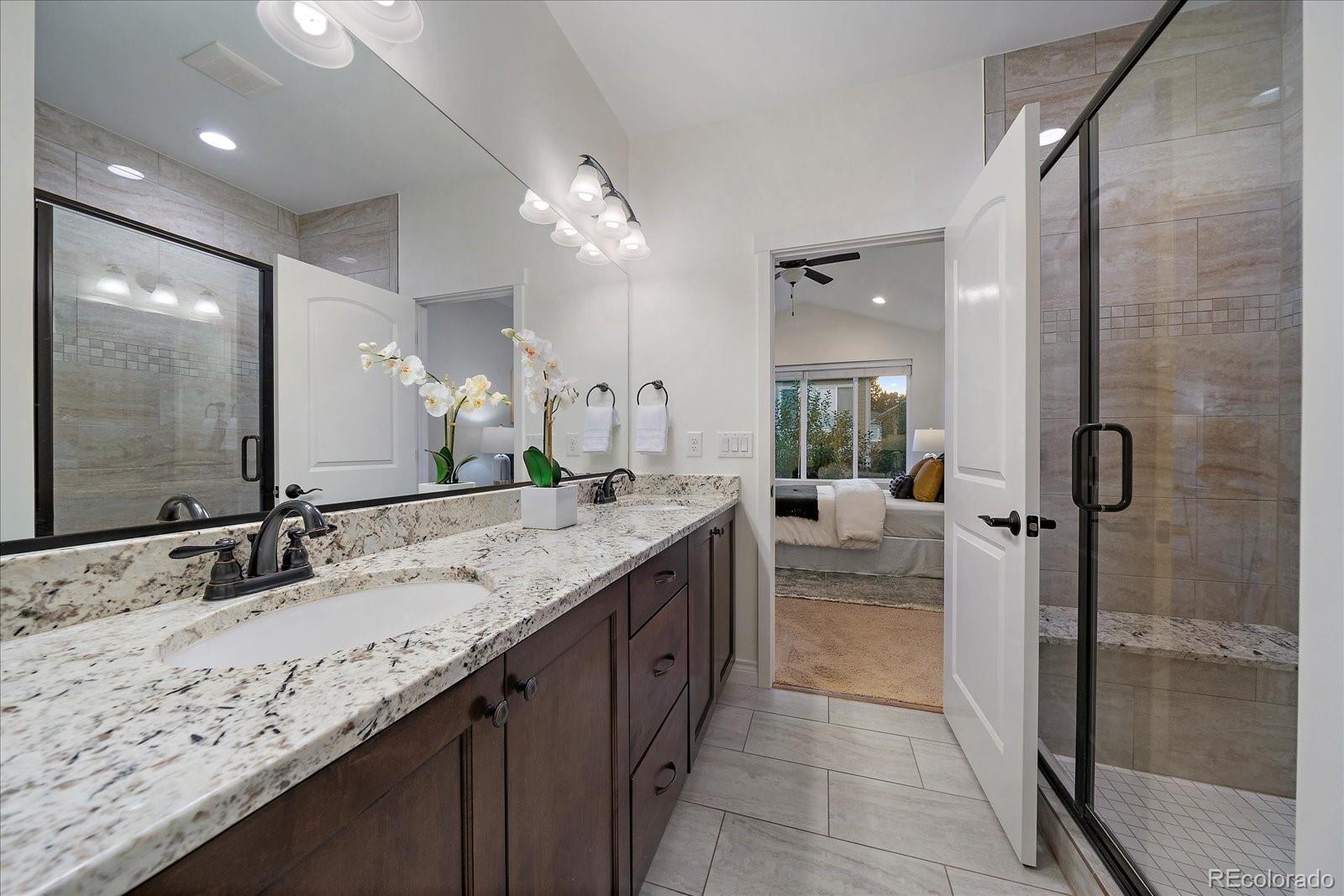 11526 Colony Loop Parker, CO 80138 - Photo 21 of 29 a bathroom with a granite countertop sink a mirror and a shower