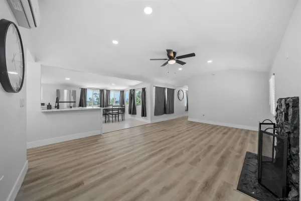 a view of an empty room with wooden floor and a bathroom